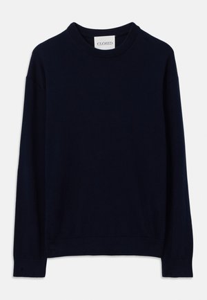 Un pull à col rond bleu marine à manches longues avec des poignets et un ourlet côtelés, présentant une petite étiquette blanche avec l'inscription "CLOSED" au niveau du col.