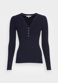 Pull marin côtelé à manches longues avec un col en V profond et une patte de boutonnage à cinq boutons. Comprend une garniture de cou intérieure contrastante. Texture douce.