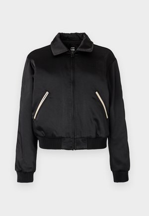 Svart sateng bomberjakke med ribbestrikket kant, som har to sidelommer med kontrasterende hvite glidelåser og en klassisk kragedesign.