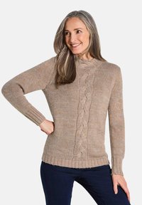 Beige Strickpullover mit einem Zopfmuster in der Mitte, rundem Halsausschnitt und gerippten Bündchen. Über dunklen Jeans getragen.