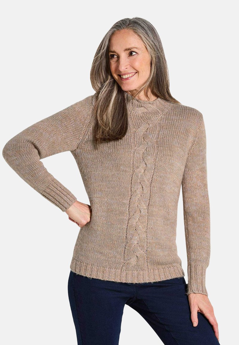 Beige Strickpullover mit einem Zopfmuster in der Mitte, rundem Halsausschnitt und gerippten Bündchen. Über dunklen Jeans getragen.