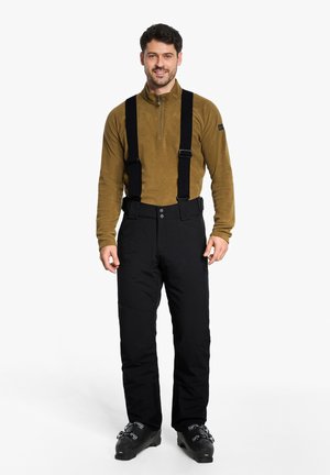 Black ski pants with adjustable suspenders, paired with a brown zip-fleece top. The material appears durable and suitable for cold conditions.