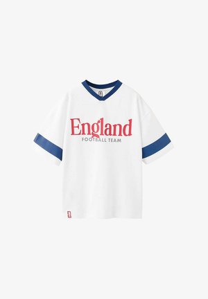 Biely futbalový dres s krátkym rukávom, námornícko modrými pruhmi na rukávoch a golieri, s červeným textom "England" a sivým textom "Football Team" vpredu.