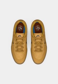 Sneakers Nike SB w jasnobrązowym zamszu, z czarnym swooshem, beżowymi sznurówkami oraz niebieskimi i brązowymi akcentami wewnętrznymi. W zestawie podeszwa gumowa.