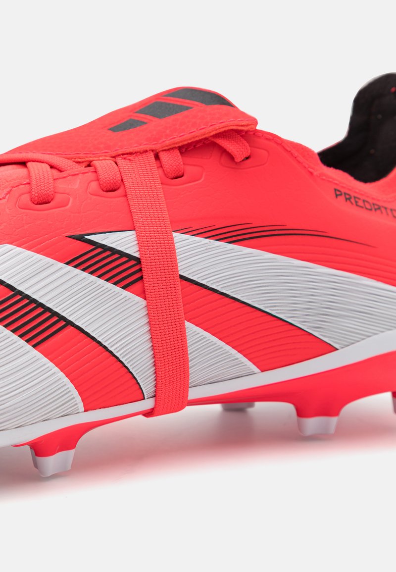 Rote Fußballschuhe mit weißen und schwarzen Streifen, strukturiertem Obermaterial, sicherem Schnürsystem und Gummistollen für Traktion auf Rasenflächen.