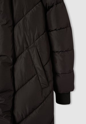 Giacca a vento nera con design a zigzag, dotata di tasca laterale e polsini a costine. Il materiale appare liscio e leggermente lucido.