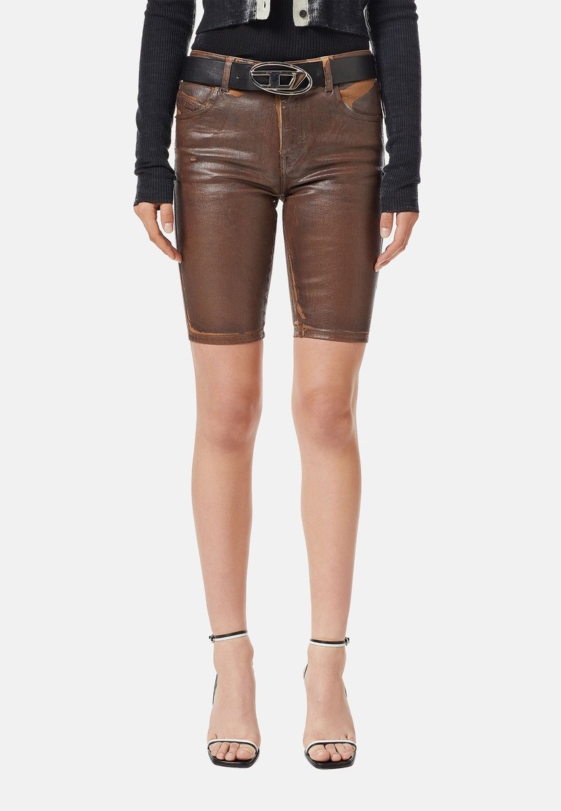 Femme portant un short en cuir marron longueur genou, ceinture noire avec boucle argentée, haut noir à manches longues côtelées, et talons hauts noirs à brides.