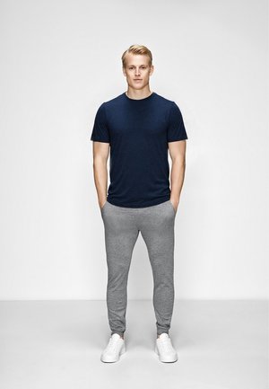 Mørkeblå crew-neck t-shirt kombineret med lysegrå joggers, der har et blødt stof og elastiske manchetter, båret med hvide sneakers.