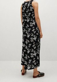 Černé maxi šaty s květinovým vzorem v bílých a modrých tónech. Mají kulatý výstřih a volný střih. Noseny s černými dřeváky.