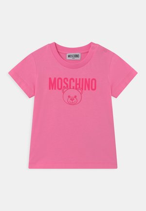 Camiseta de algodón rosa con cuello redondo, mangas cortas y un gráfico de un oso con el texto "MOSCHINO" impreso en negrita arriba.