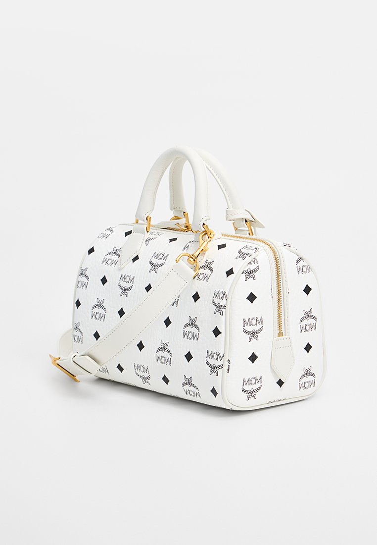 Weiße Lederhandtasche mit schwarzem MCM-Logo-Muster, goldfarbener Hardware, doppelten Griffen und einem abnehmbaren Schultergurt. Strukturierte Form.