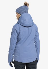 Hellblau isolierte Jacke mit Kapuze, Reißverschlusstaschen und strukturierter Strickmütze mit Bommel. Handschuhe werden an den Händen getragen.