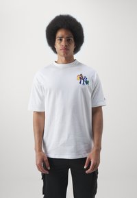 Camiseta de algodón blanca de manga corta, con un diseño gráfico colorido en el pecho que representa flora estilizada y letras.