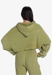 Geknipte, geribbelde hoodie in olijfgroen met een grote capuchon, voorzien van oversized mouwen en een tailleband, gecombineerd met bijpassende geribbelde broeken.