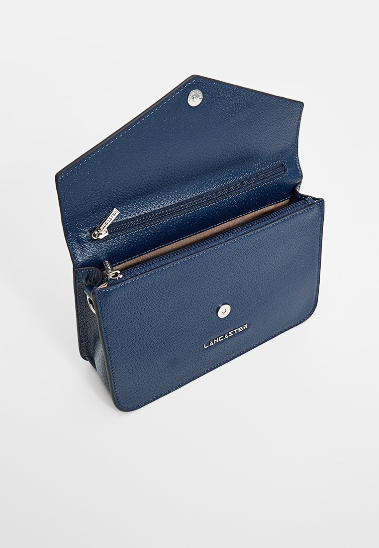 Marineblaues Lederportemonnaie mit strukturiertem Finish, ausgestattet mit einem Reißverschlussfach und Druckknopfverschluss. Das "LANCASTER"-Logo ist auf der Vorderseite geprägt.