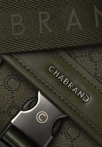 Sangle en tissu vert avec le logo embossé "CHABRAND" et des accents texturés, dotée d'un fermoir métallique et de coutures détaillées.