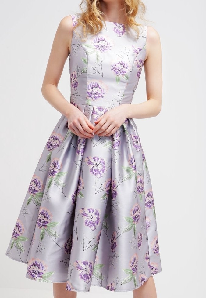 Kukallinen painettu mekko vaalean lilassa satiinissa, hihaton, istuva bodice ja liehuva hame, jossa on vihreät lehtikoristeet.