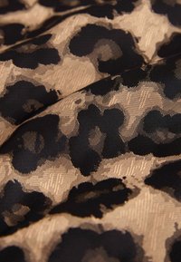 Leopardų rašto audinys su juodais taškais ant smėlio spalvos fono, turintis tekstūrinį, austą paviršių. Minkštas, patvarus medžiaga.