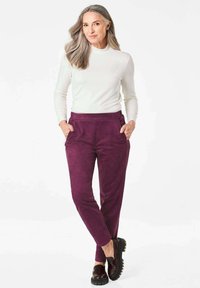 Paarse suède broek met zijzakken en een rechte pasvorm, gecombineerd met een aansluitend wit shirt met lange mouwen en zwarte platform schoenen.