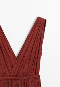 Rust-colored dress featuring a deep V-neck and pleated fabric, gathered at the waist with a matching belt. Background is white.
