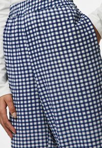 Lätta, marinhals- och vita rutiga byxor med elastiskt midjeband och sidofickor, med en texturerad tygfinish.