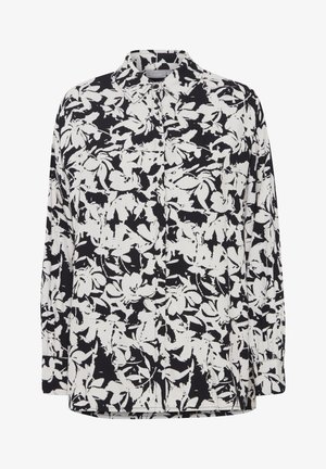 Mustavalkoinen kukkamyssy, jossa on pitkät hihat, napitettu etuosa, kauluksessa oleva kaulus ja teksturoitu kangas, jossa on rohkea, kontrastinen kuvio.