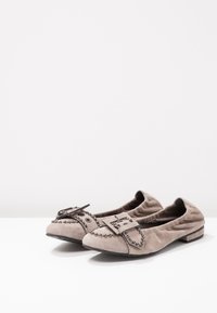 Ballerine in suede grigio chiaro con fibbia decorativa e dettagli borchiati. Punta rotonda e tacco basso impilato per il comfort.