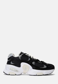 Svarta och gråa sportskor i mesh och mocka, vit sula, distinkt vågmönster på sidorna och beige detaljer.