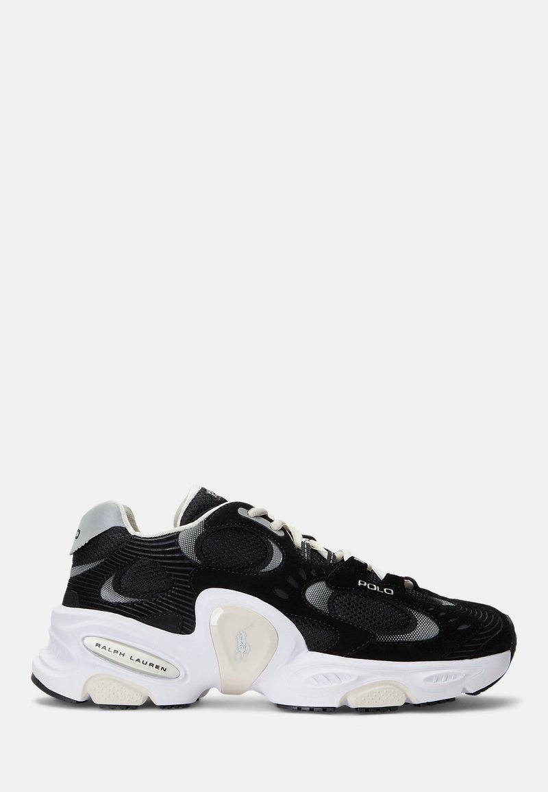 Svarta och gråa sportskor i mesh och mocka, vit sula, distinkt vågmönster på sidorna och beige detaljer.