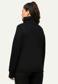 Zwarte fleece pullover met een hoge kraag, lange mouwen en een relaxte fit. Opvallend roze ritssluiting detail aan de achterkant van de nek.