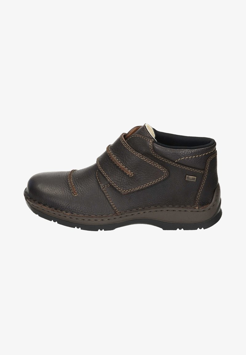 Brown leather shoe with two Velcro straps, rounded toe, and contrasting stitching. Low heel and rubber sole for grip.
