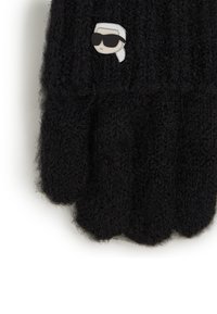 Black knitted gloves made of fuzzy material, featuring a cartoon pin of a person with sunglasses on the wrist. Textured and cozy design.