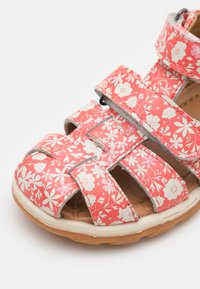 Rosa floral-mønstret sandal med flere stropper, laget av fleksibelt syntetisk materiale, med gummisåle og polstret innersåle.