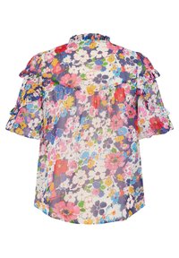 Blouse à manches courtes avec volants et motif floral coloré en rose, bleu, jaune, blanc et vert sur un fond clair.