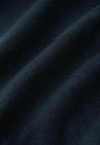 Tissu bleu foncé avec une surface texturée, présentant des vagues subtiles et une apparence douce et tricotée.