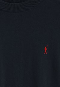 Pull marin en tissu tricoté doux, avec un petit logo de golfeur rouge brodé sur la poitrine gauche. Design classique à col rond.