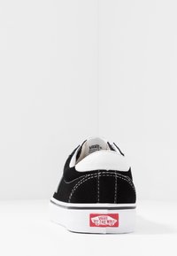 Black suede Vans sneakers with a white sole and heel, featuring the "Off the Wall" logo on the back against a plain white background.