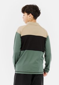 Groene, zwarte en beige langemouwen shirt met een hoge kraag en een kleurgeblokkeerd ontwerp. Gladde textuur met contrasterende stikdetails.