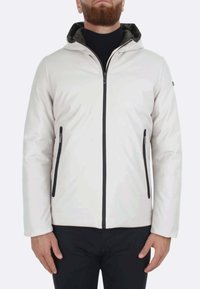 Giacca bianca con cappuccio, chiusura frontale con zip nera e tasche laterali. Presenta una superficie liscia e un rivestimento interno scuro a contrasto. Design semplice.