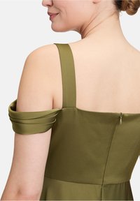 Olivengrünes Kleid mit schulterfreien Ärmeln, ausgestattet mit einem Reißverschluss auf der Rückseite und einer glatten, satinartigen Textur.