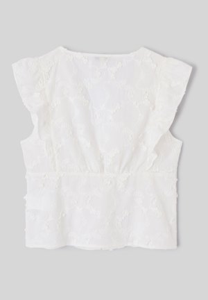 Blouse blanche sans manches avec broderie florale et détails à volants sur les épaules, présentée sur un fond gris uni.