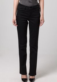 Los jeans de mezclilla negra presentan un corte recto con cinco bolsillos y una textura suave. La cinturilla incluye un cierre de botón en la parte frontal.