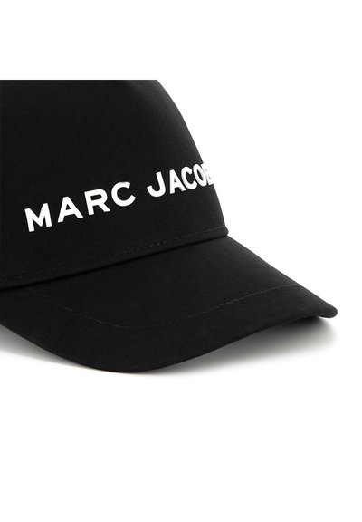 Zwarte pet gemaakt van textuurstof met een gebogen rand. Voorzien van witte letters die "MARC JACOBS" op de voorkant spellen.
