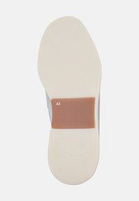 Suola della scarpa con una base beige chiaro, dotata di un inserto in gomma marrone etichettato '43'. Il design è liscio con texture curve e dettagli minimi.