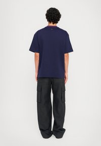 Navy oversized t-shirt with short sleeves, paired with black cargo pants featuring multiple pockets and a relaxed fit.