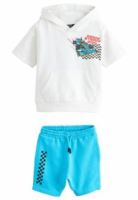 Haut à manches courtes blanc avec un graphique de voiture de course et poche kangourou. Associé à un short bleu avec un motif écossais noir sur le côté.