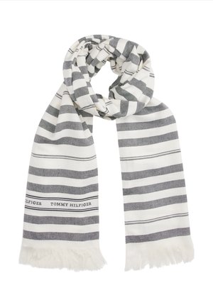 Biały szalik z czarnymi poziomymi paskami i frędzlami na końcach, z napisem "Tommy Hilfiger" blisko jednego brzegu.