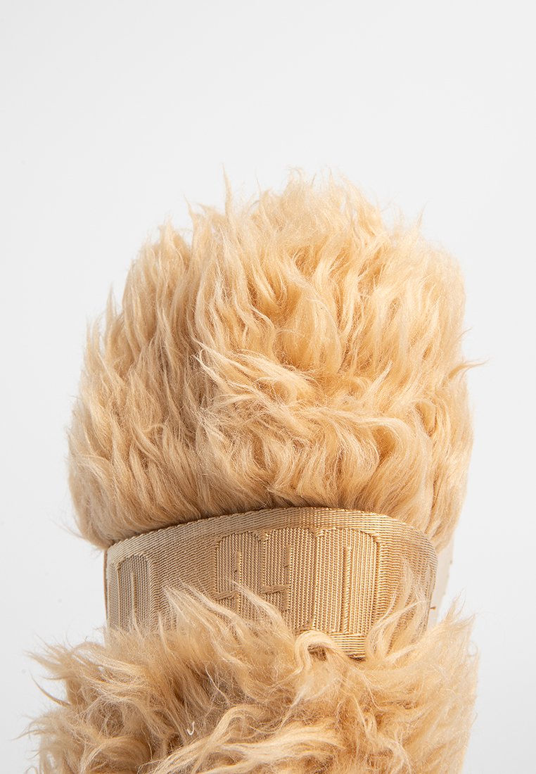 Fourrure fluffy brun clair avec une large bande en tissu de couleur assortie l'entourant, texture contrastant avec un fond blanc uni.