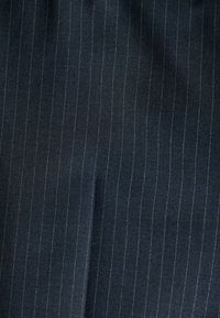 Tissu gris foncé avec fines rayures verticales gris clair et plis légers.