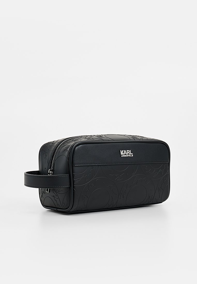 Borsa da toilette in pelle nera con motivo a rilievo della firma, chiusura con zip e manico laterale. Presenta un logo metallico sul davanti.